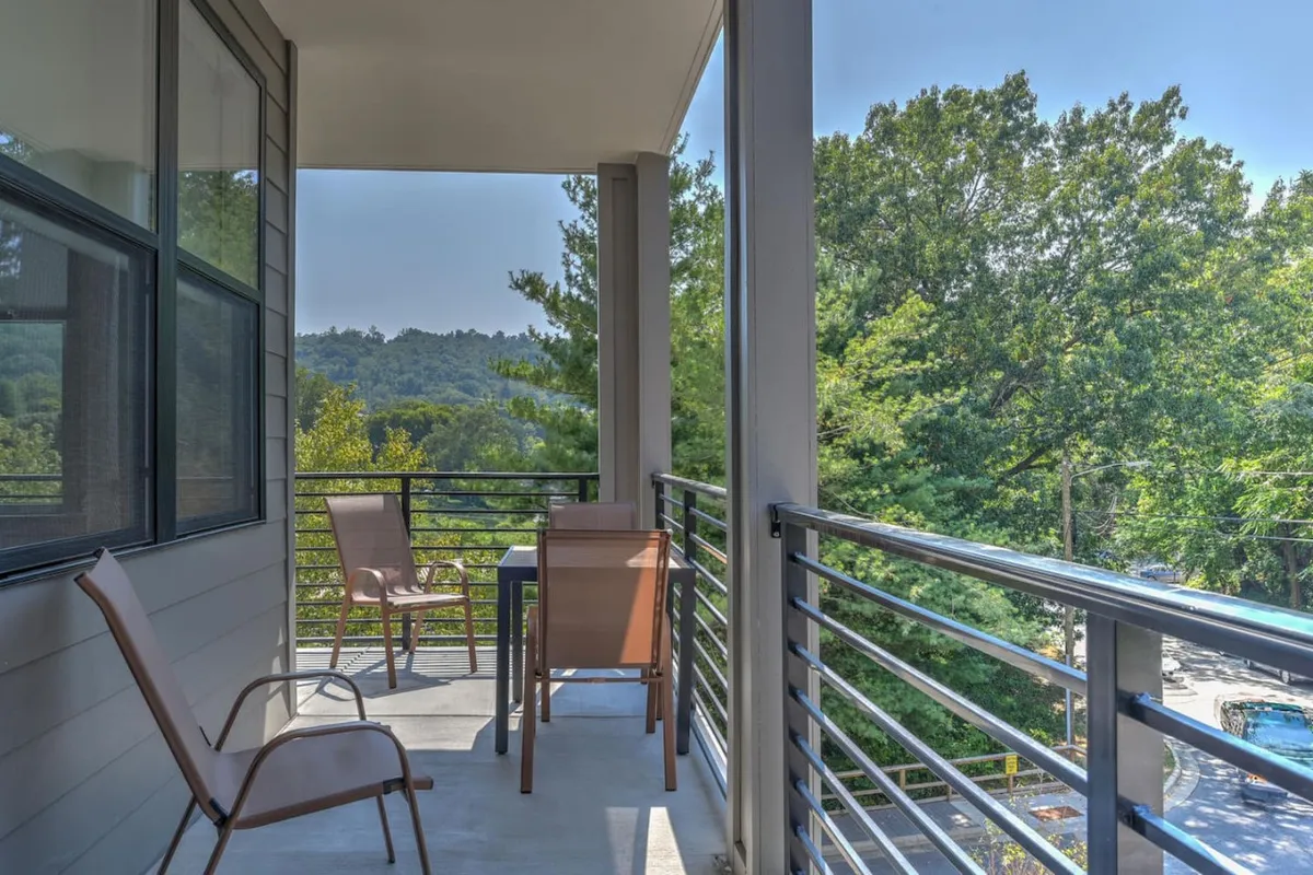 A private balcony setup with comfortable seating, surrounded by lush natural landscape and expansive mountain vistas. The scene emphasizes peaceful relaxation, whether sipping morning coffee or simply soaking in the atmosphere. The view highlights both the connection to the outdoors and the intimate retreat offered by the balcony.