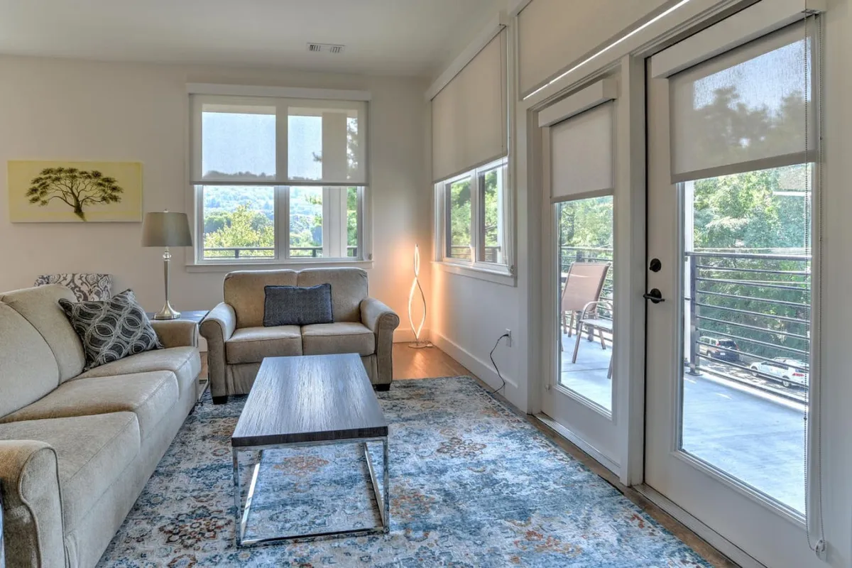 A comfortable seating area featuring a sofa, coffee table, stylish wall art, and windows letting in natural light. The ambiance is relaxed, making it perfect for morning coffee or evening wind-downs after exploring the neighborhood.