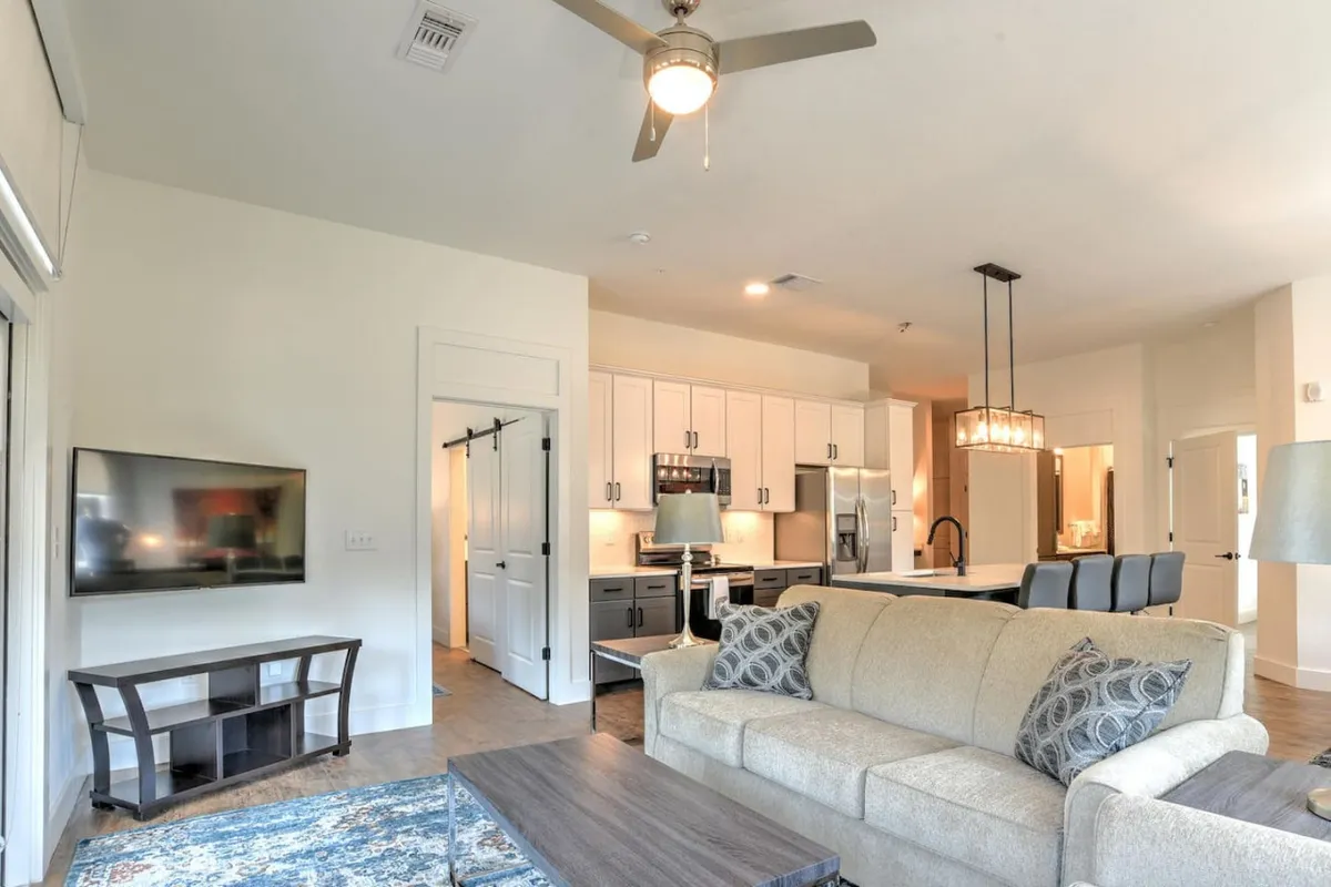 An open-concept living area where the kitchen flows seamlessly into a comfortable lounge. The scene features a plush sofa, a coffee table, a kitchen island, and a television, creating a setting ideal for relaxing, entertaining, or casual meals with family and friends.